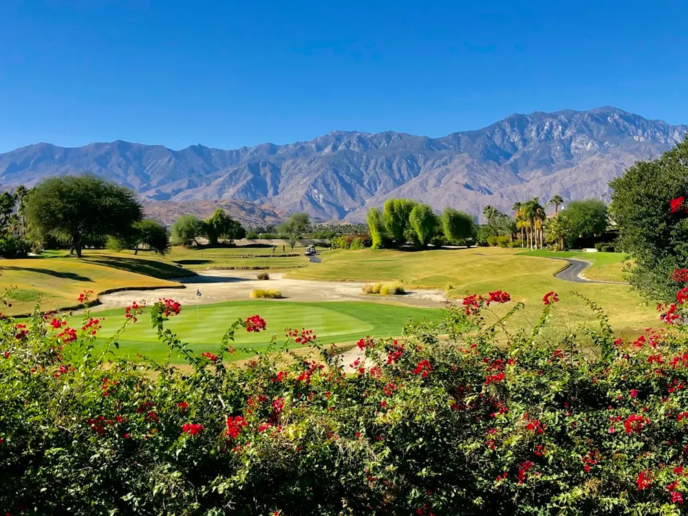 Golf course in a green valley below mountains