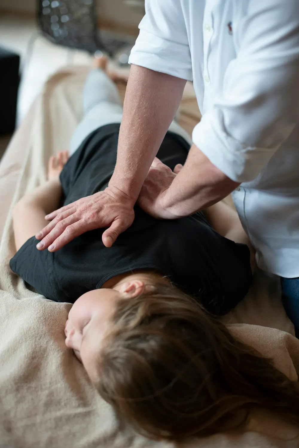 Therapist giving a traditional Thai massage to a fully clothed guest