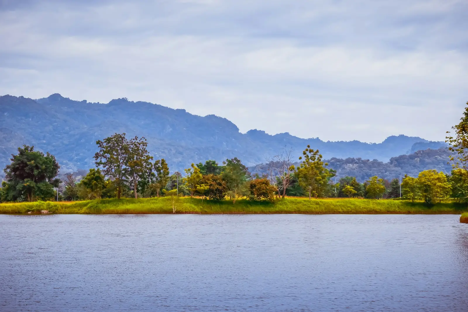 Calm lake surrounded by green fields and mountains